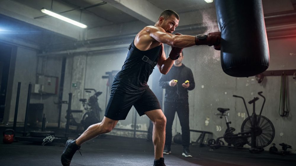 A gritty, realistic photo of a boxer smashing a heavy bag in a gym,